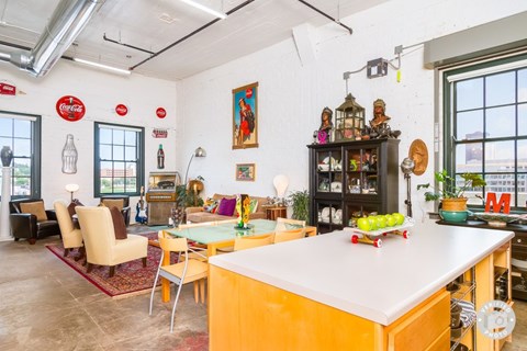 A kitchen with a yellow island and a dining table with chairs.